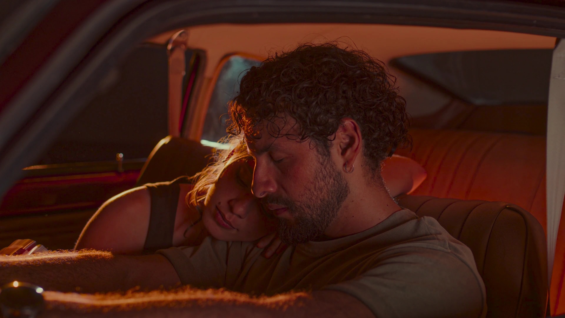 A couple asleep in a car at night, graded warm in Leumos