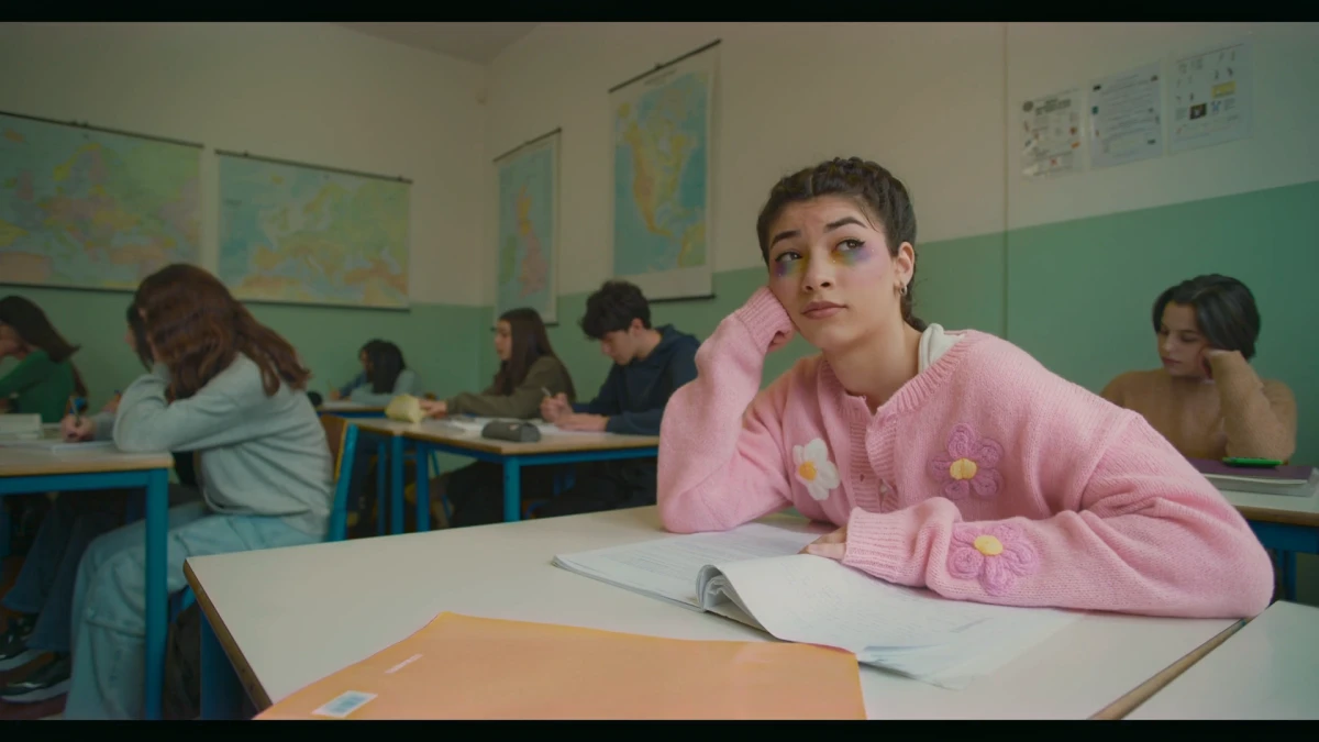 Leumos output: the same classroom frame after matching to the reference, with warmer highlights, deeper midtones, more saturation, the foreground folder shifted from yellow toward orange